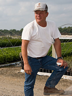 Photo: Farmer near greenhouses.